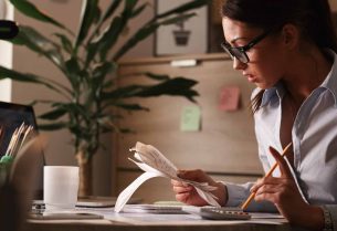 Young businesswoman going through finances and analyzing bills in the office.